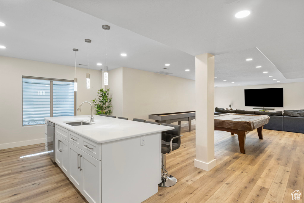 Kitchen featuring pool table, light hardwood / wood-style flooring, sink, white cabinets, and a kitchen island with sink