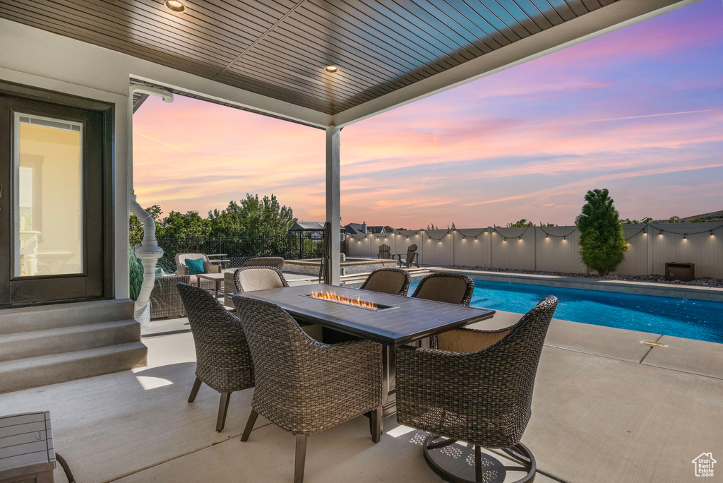 Patio terrace at dusk with a fenced in pool