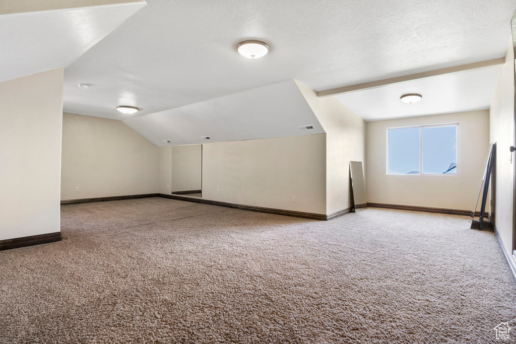 Bonus room with carpet floors, a textured ceiling, and vaulted ceiling