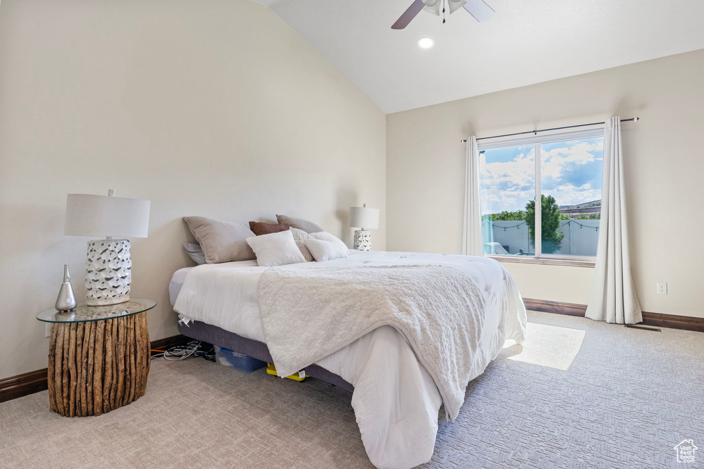 Carpeted bedroom featuring ceiling fan and vaulted ceiling