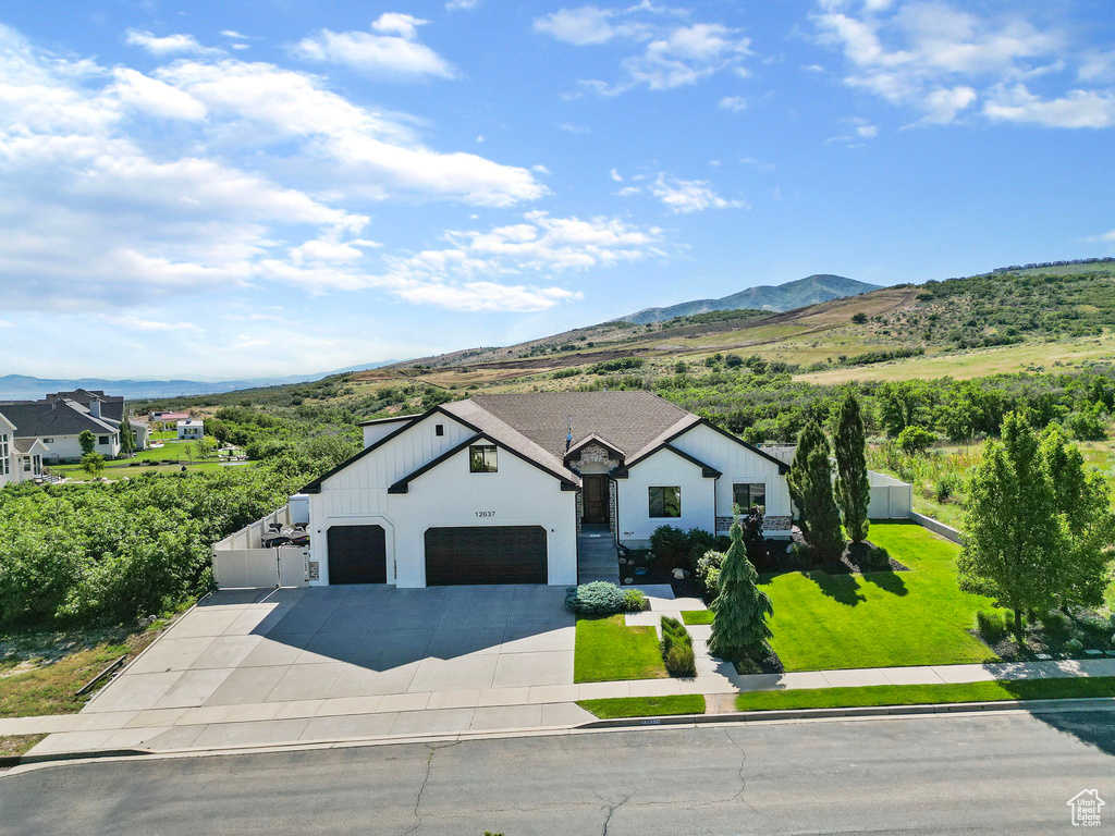 View of front facade with a garage, a mountain view, and a front yard