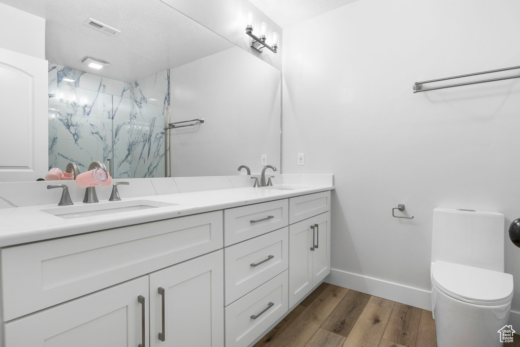 Bathroom with dual sinks, a shower, hardwood / wood-style floors, oversized vanity, and toilet