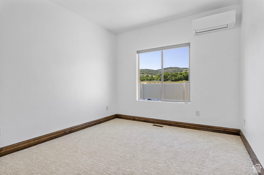 Carpeted spare room featuring an AC wall unit