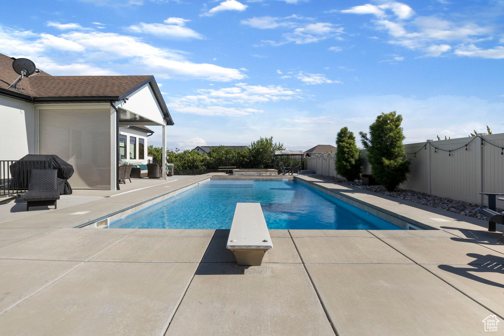 View of pool with a diving board and a patio