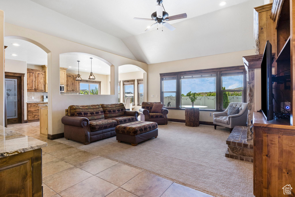 Tiled living room with plenty of natural light, ceiling fan, and lofted ceiling