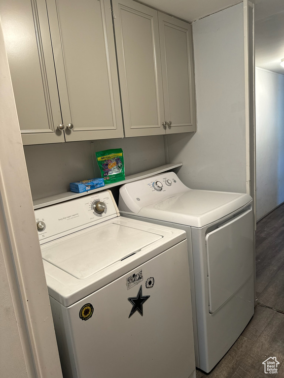 Washroom with separate washer and dryer, dark wood-type flooring, and cabinets