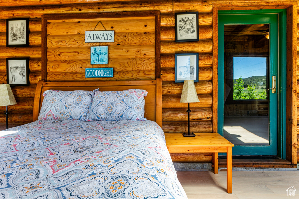 Bedroom with log walls and wood-type flooring