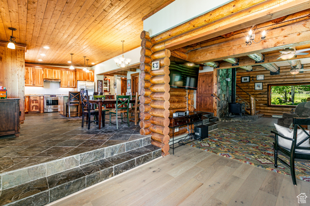 Dining space featuring wooden ceiling, ceiling fan with notable chandelier, rustic walls, and wood-type flooring