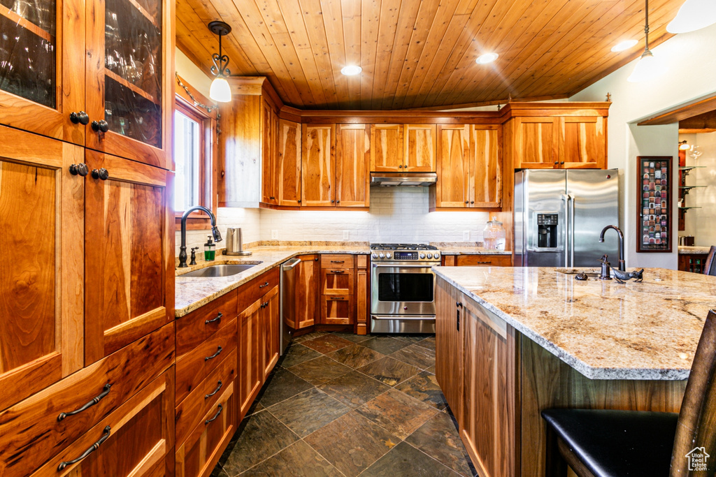 Kitchen featuring decorative light fixtures, dark tile floors, stainless steel appliances, wood ceiling, and sink