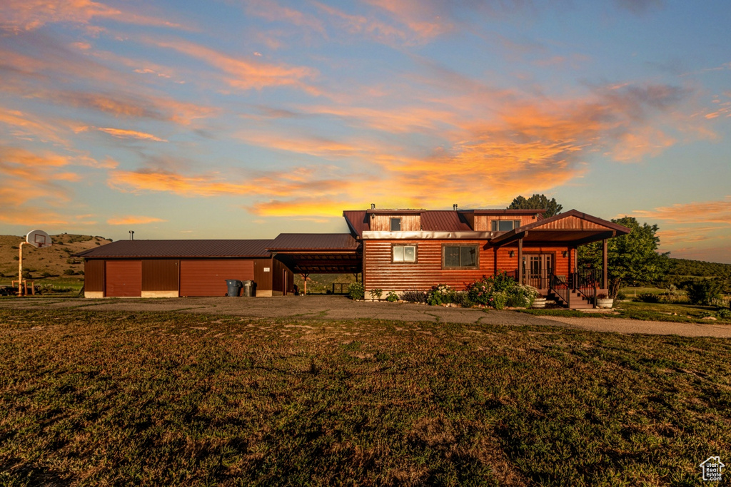 Back house at dusk featuring an outdoor structure and a yard