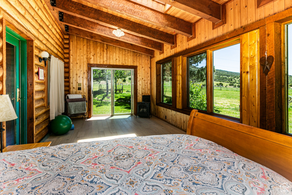 Unfurnished bedroom featuring access to exterior, log walls, hardwood / wood-style floors, wood ceiling, and lofted ceiling with beams