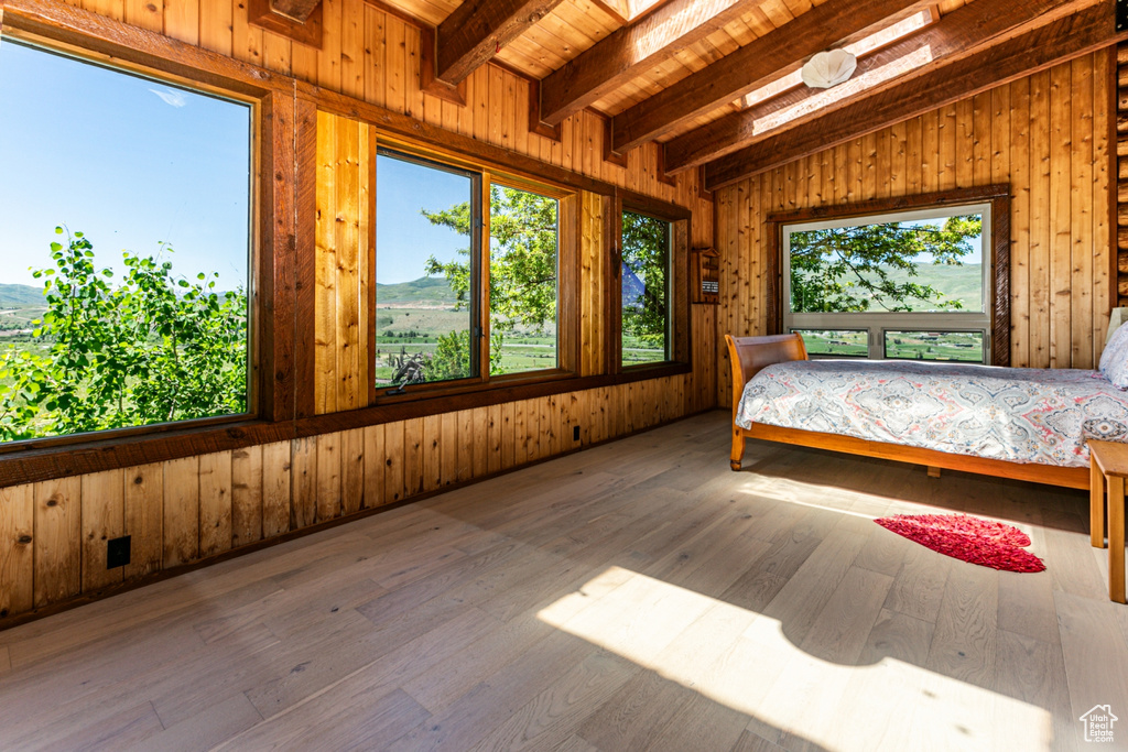 Unfurnished bedroom with vaulted ceiling with beams, hardwood / wood-style floors, and wooden walls