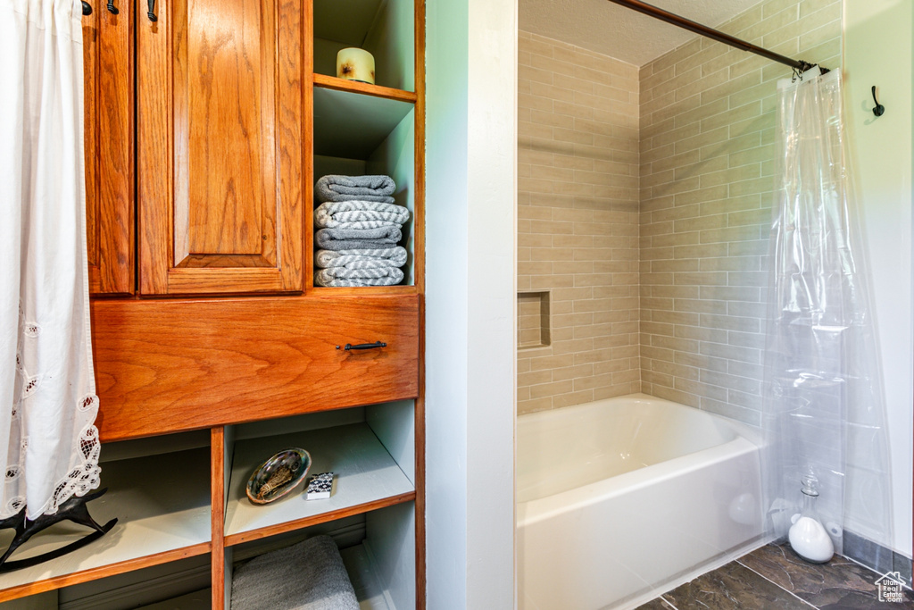 Bathroom with tile flooring and shower / bathtub combination with curtain