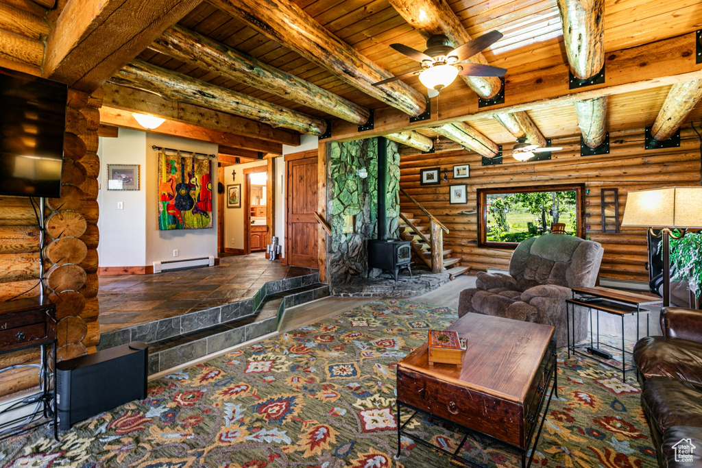 Living room featuring ceiling fan, beamed ceiling, wood ceiling, rustic walls, and a wood stove