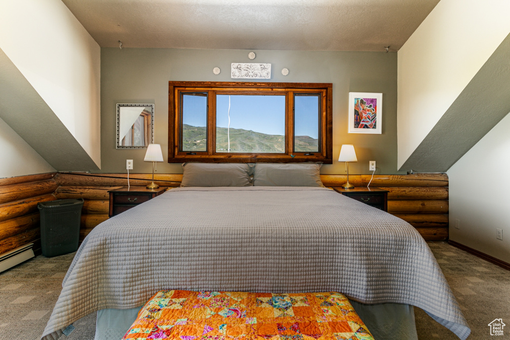 Bedroom with a textured ceiling, carpet flooring, and rustic walls