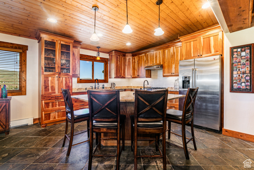 Kitchen with baseboard heating, dark tile flooring, high end refrigerator, and pendant lighting