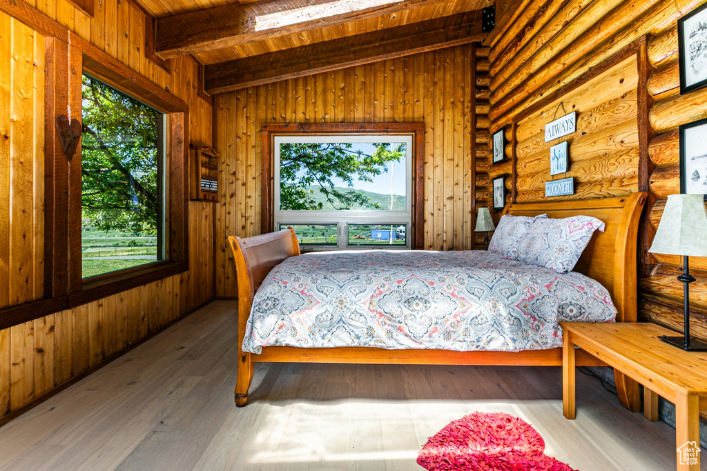 Bedroom with wooden ceiling, hardwood / wood-style flooring, vaulted ceiling with beams, and log walls