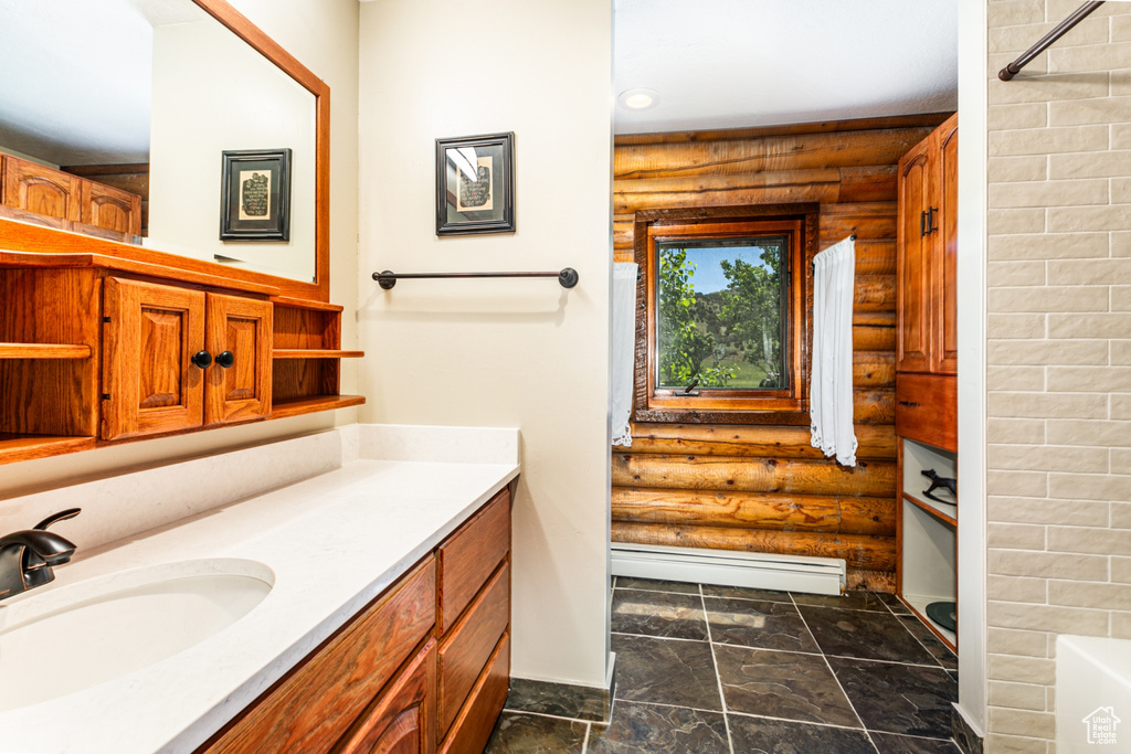 Bathroom with tile flooring, rustic walls, large vanity, and baseboard heating