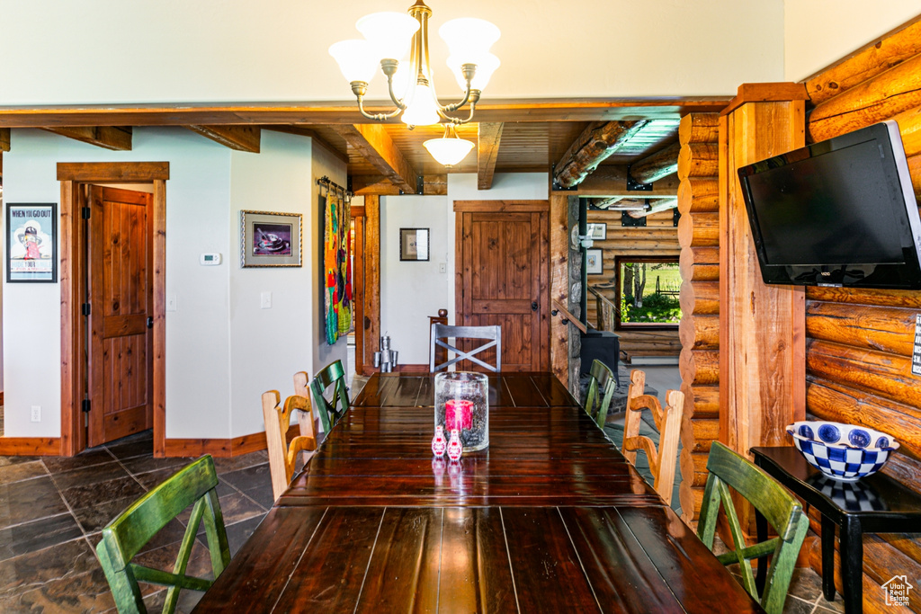 Dining room with beamed ceiling, tile flooring, log walls, and an inviting chandelier