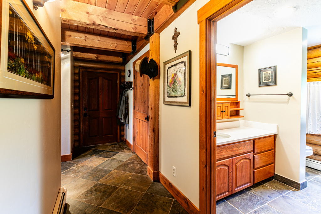 Hall with a baseboard heating unit, dark tile floors, beam ceiling, and wood ceiling