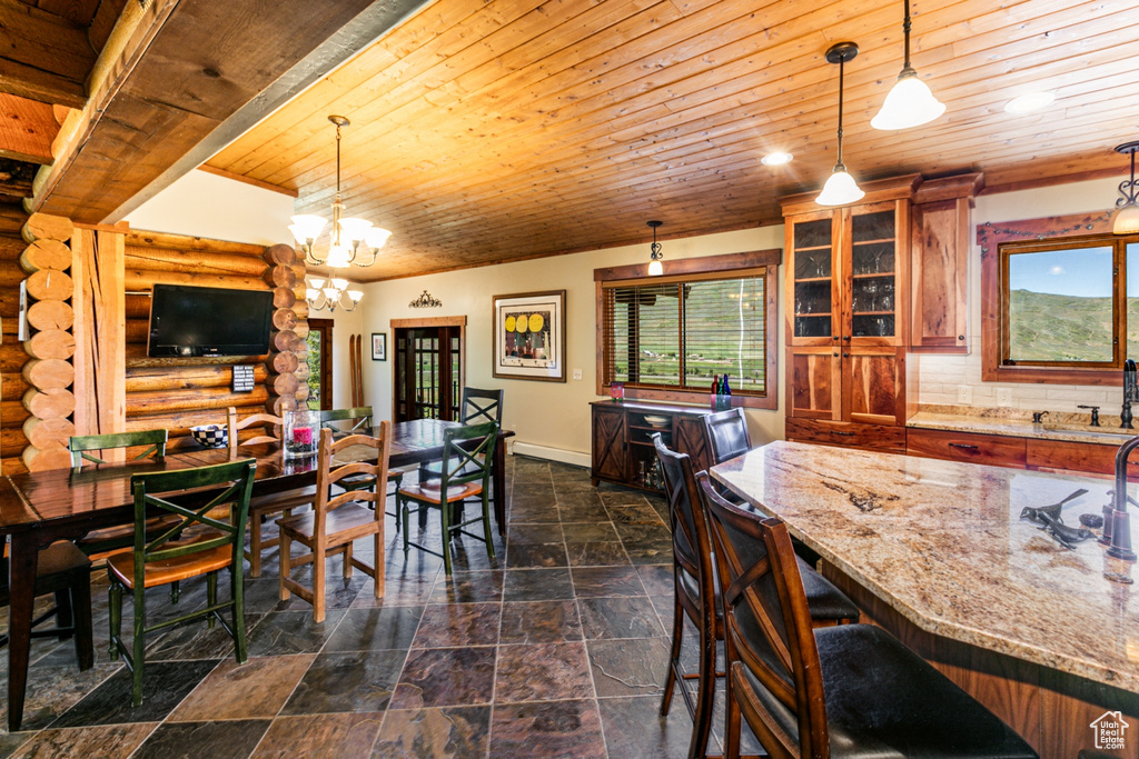 Tiled dining space featuring a notable chandelier, sink, rustic walls, and wooden ceiling