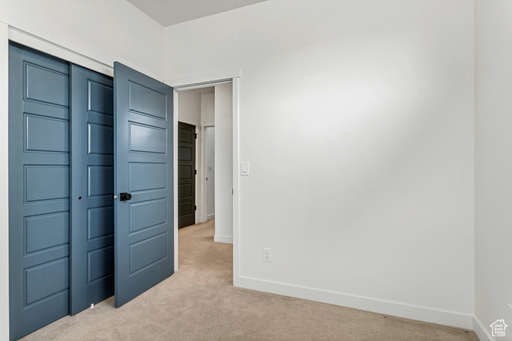 Unfurnished bedroom featuring light carpet and a closet