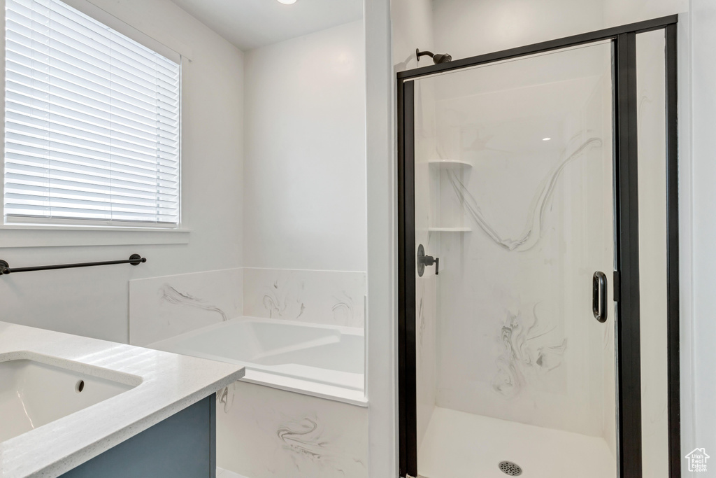 Bathroom with a healthy amount of sunlight, separate shower and tub, and vanity