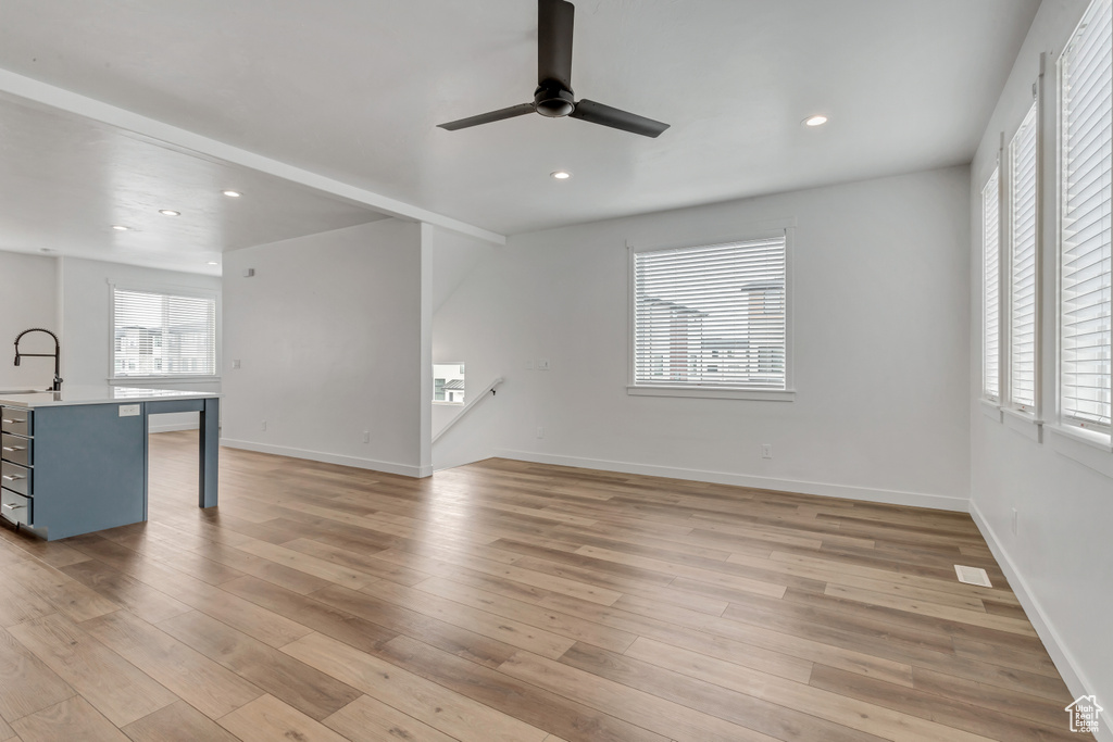 Living room with ceiling fan, light hardwood / wood-style flooring, and sink