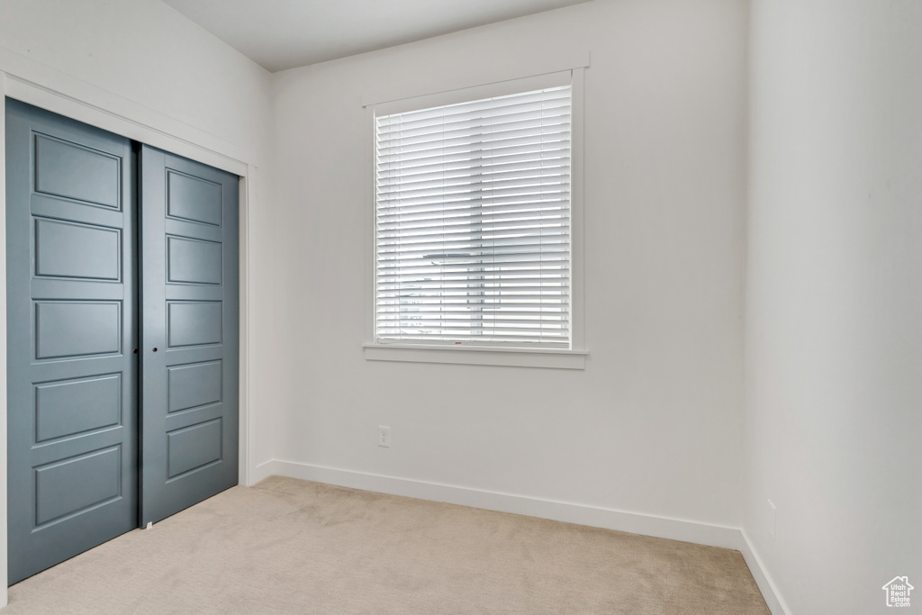 Unfurnished bedroom with a closet, carpet, and multiple windows