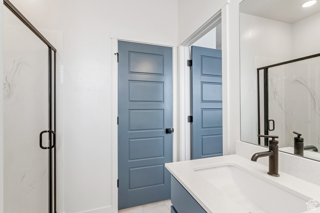 Bathroom featuring oversized vanity, tile floors, and a shower with door