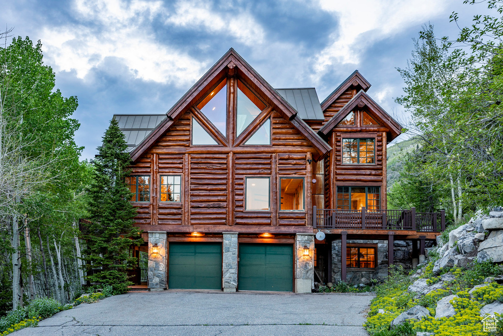 Log-style house featuring a garage and a balcony