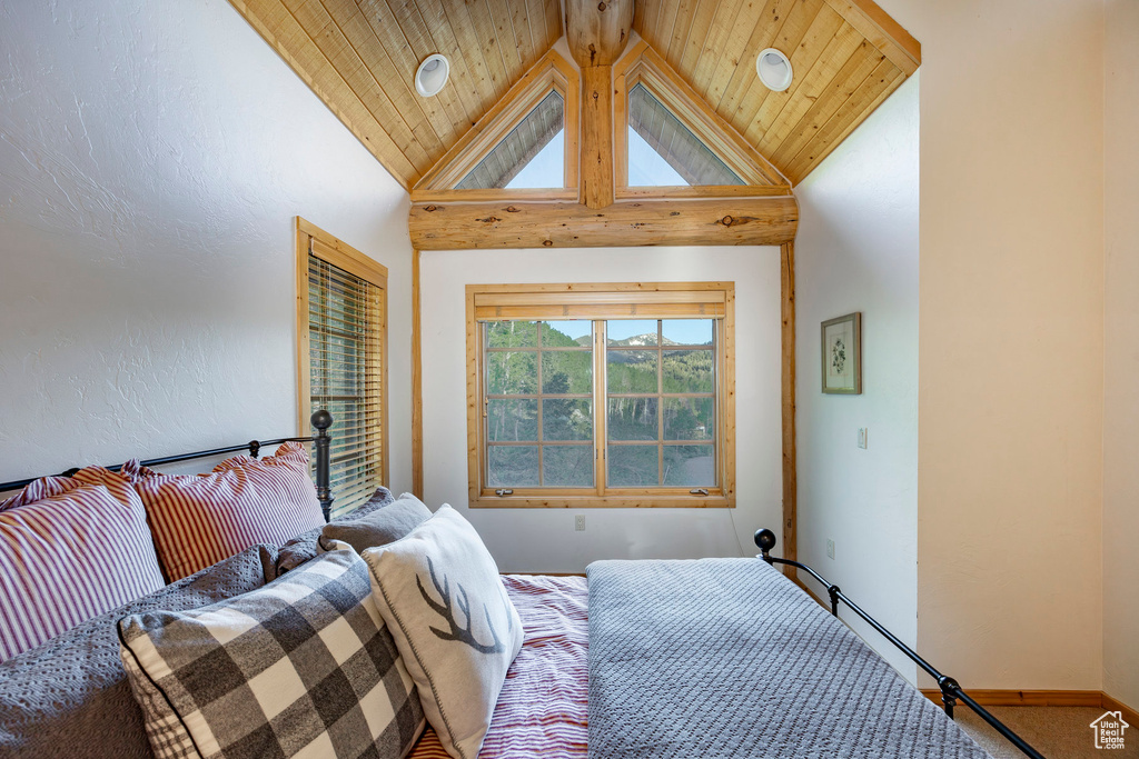 Carpeted bedroom featuring high vaulted ceiling and wooden ceiling