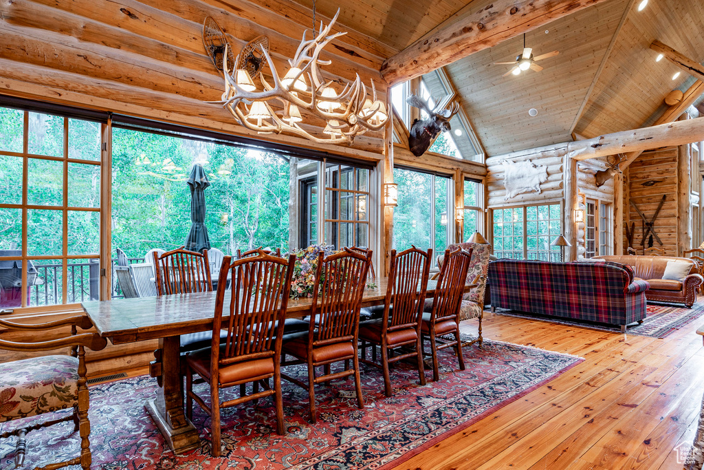 Dining room with wooden ceiling, high vaulted ceiling, ceiling fan with notable chandelier, and hardwood / wood-style floors