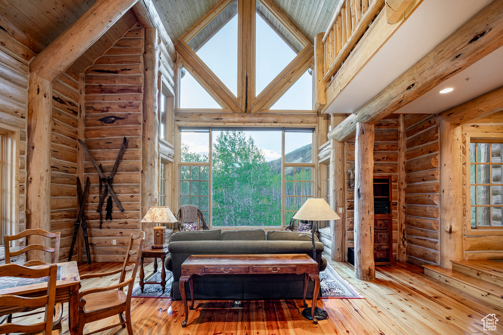 Living room with high vaulted ceiling, log walls, and hardwood / wood-style floors