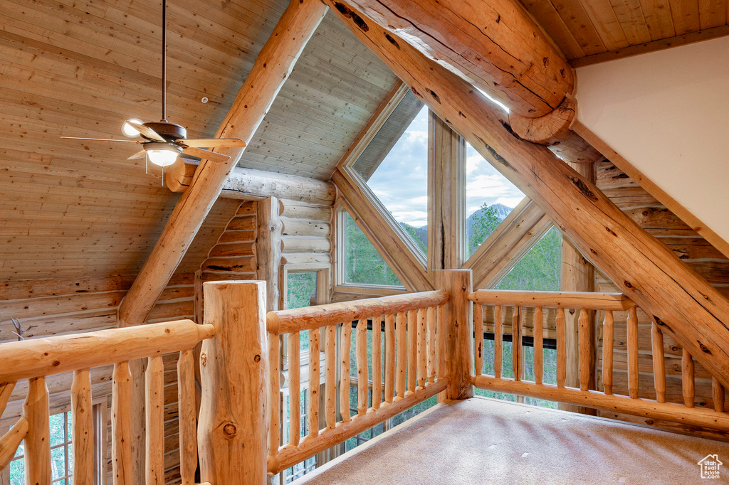 Interior space with log walls, wooden ceiling, lofted ceiling with beams, and carpet floors