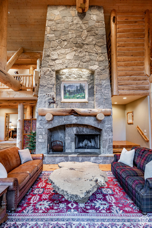 Living room with a towering ceiling, hardwood / wood-style floors, log walls, and a fireplace