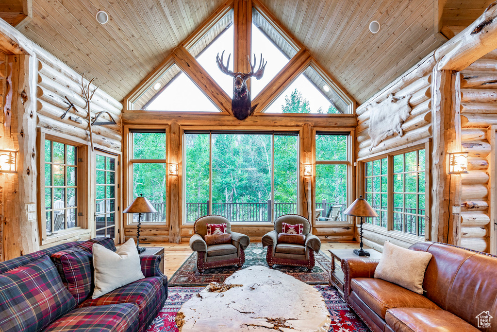 Living room featuring high vaulted ceiling, wooden ceiling, log walls, and hardwood / wood-style floors