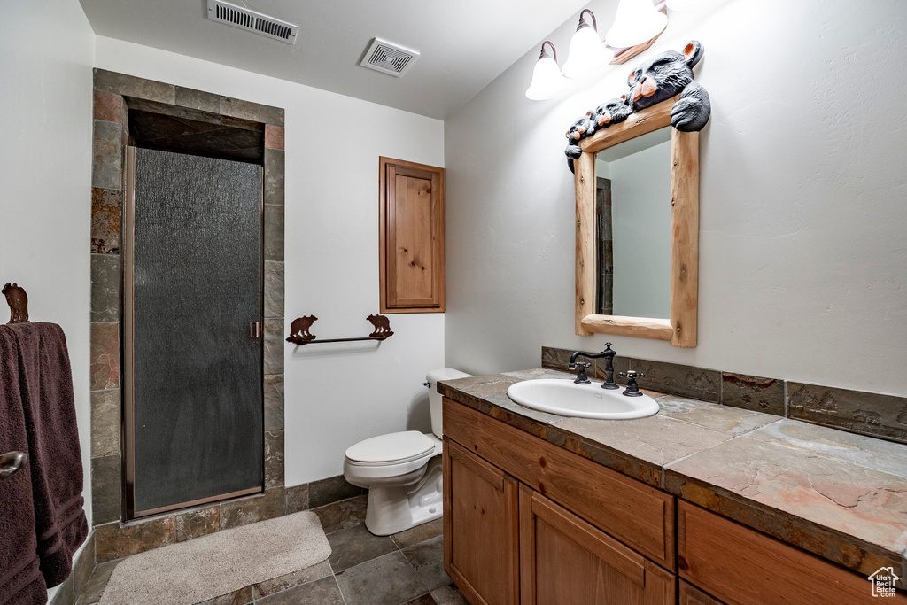 Bathroom with walk in shower, tile flooring, vanity, and toilet