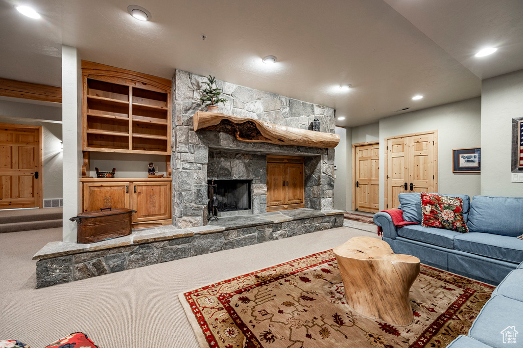 Carpeted living room with built in shelves and a stone fireplace