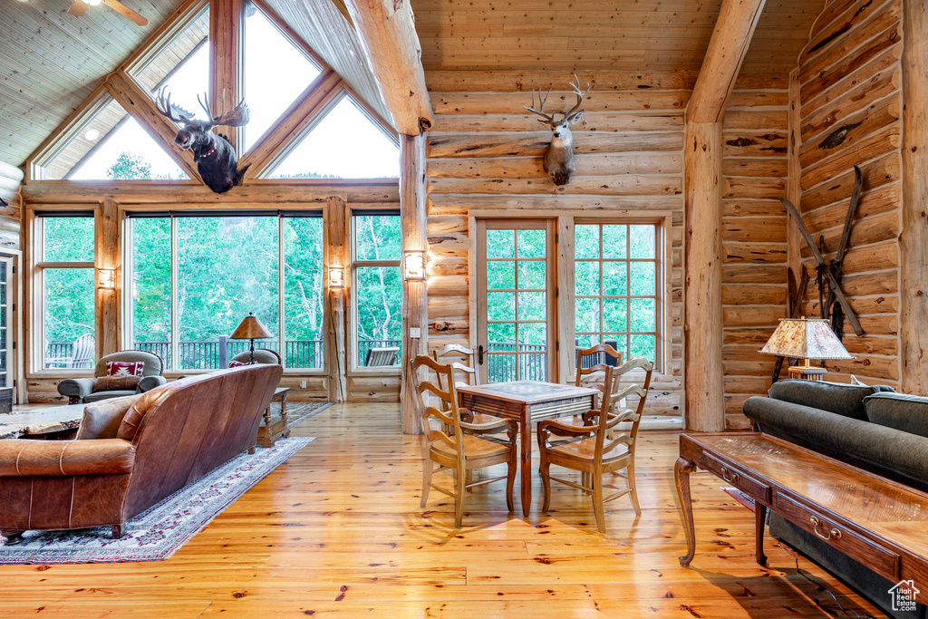 Dining area with high vaulted ceiling, light hardwood / wood-style floors, and rustic walls