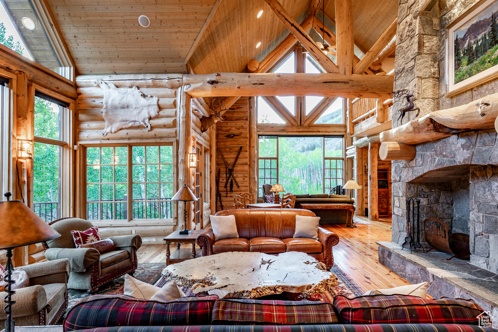 Living room featuring a fireplace, hardwood / wood-style flooring, wooden ceiling, high vaulted ceiling, and log walls