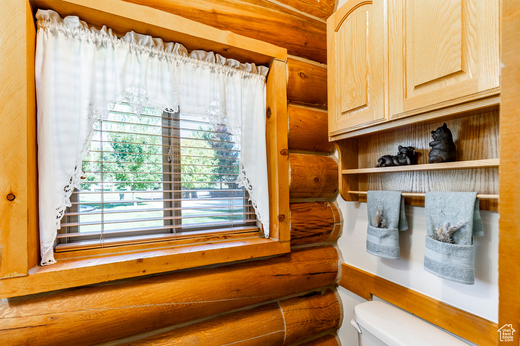 Bathroom featuring toilet and log walls