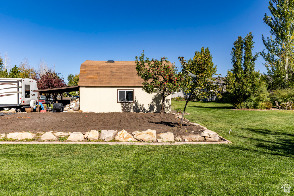 View of side of property featuring a yard, roof with shingles, and stucco siding