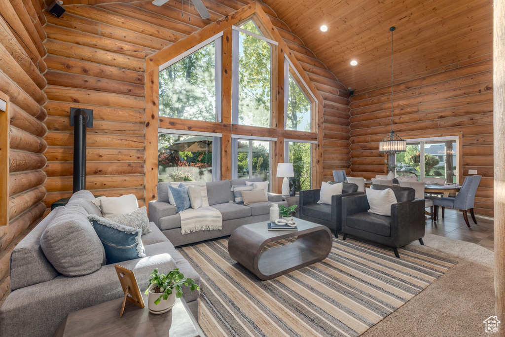 Living room with high vaulted ceiling, wood ceiling, recessed lighting, rustic walls, and a chandelier