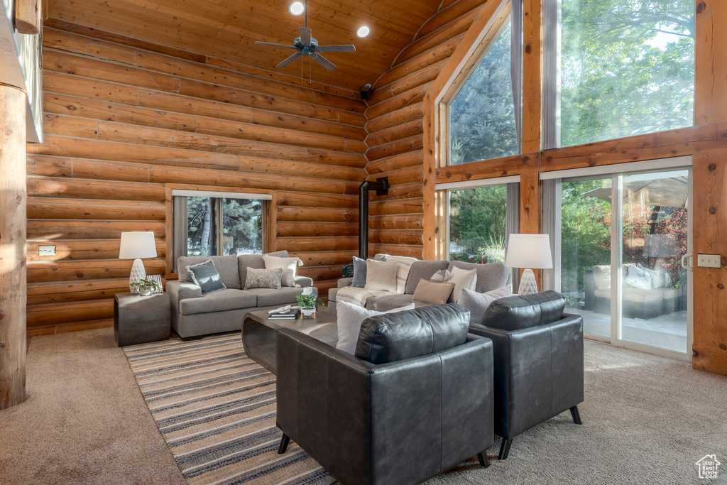 Living room featuring high vaulted ceiling, carpet flooring, wood ceiling, ceiling fan, and rustic walls