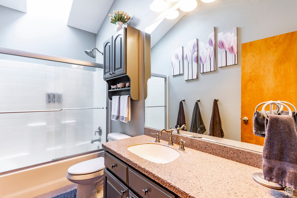 Bathroom with toilet, vanity, and enclosed tub / shower combo
