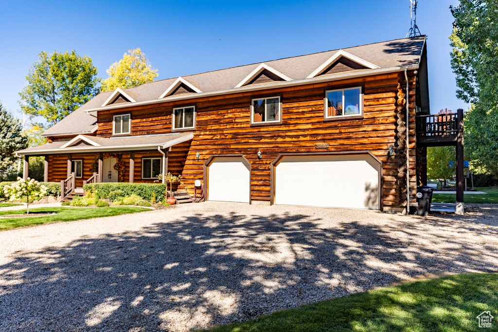 Log-style house with a porch, log exterior, and driveway