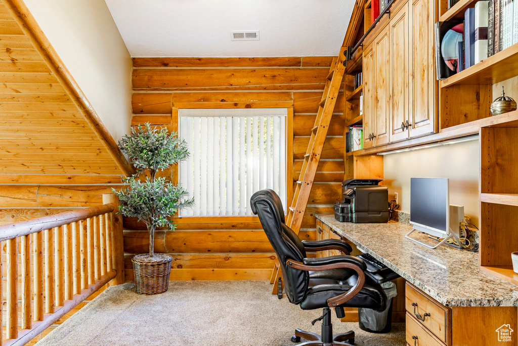 Office featuring rustic walls and carpet