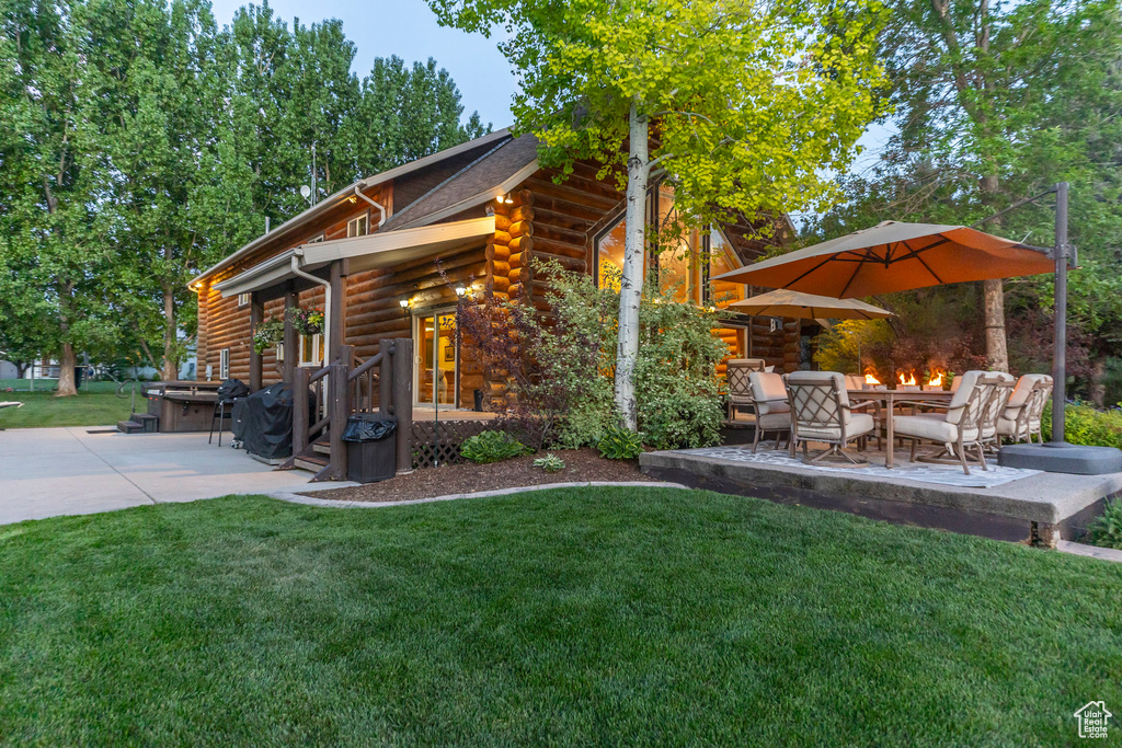 View of home\'s exterior featuring a patio, log siding, a yard, and a fire pit