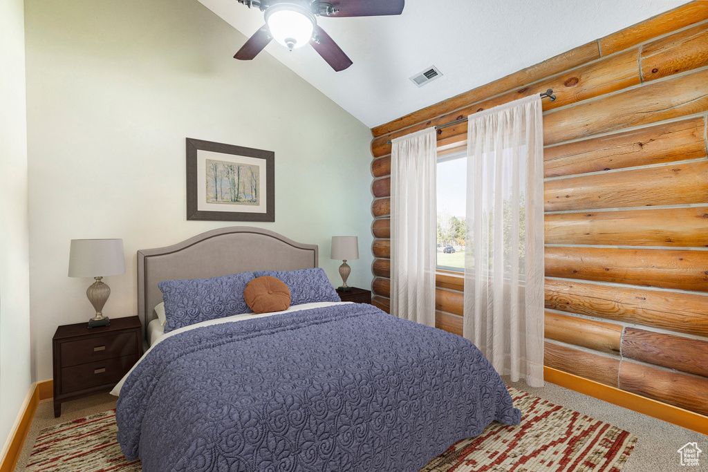 Carpeted bedroom featuring log walls, lofted ceiling, baseboards, and ceiling fan